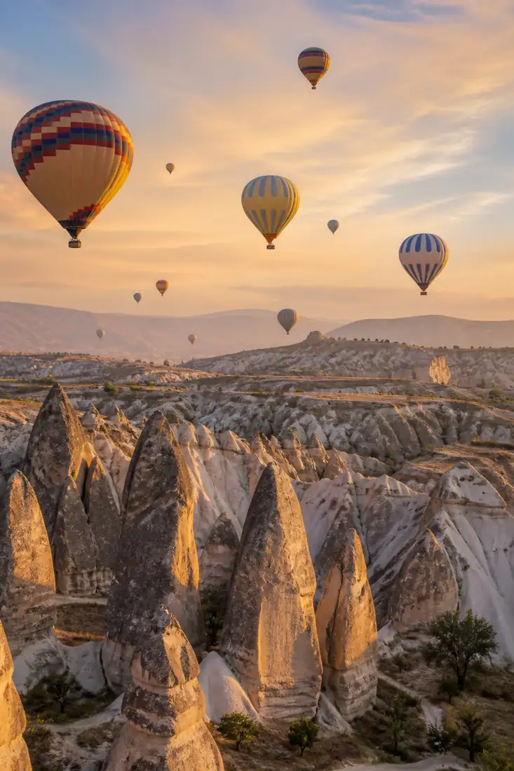 Felsformationen und Täler Kappadokiens mit Heißluftballons im goldenen Morgenlicht